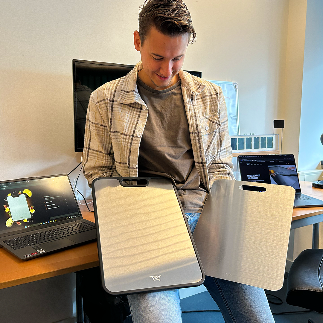 Persoon houdt twee TitanChef RVS snijplanken vast tijdens een productpresentatie in een kantooromgeving.